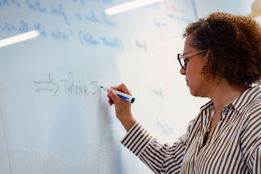 SCOR employee in a work session, writing on a whiteboard to structure a brainstorming session or business workshop, representing analytical expertise