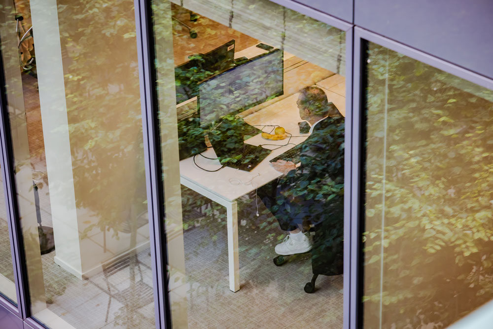 SCOR employee focused on his screens in a modern environment illustrating reinsurance expertise and innovation