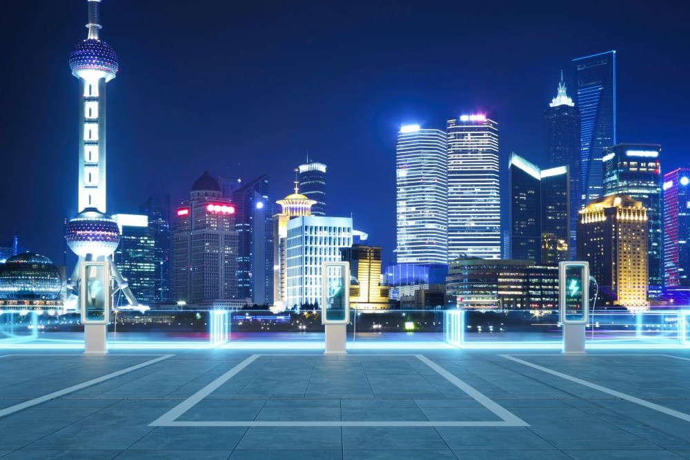 Electric vehicle charging station illuminating shanghai skyline at night 