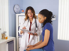 African American patient explaining issues to Asian doctor using tablet 