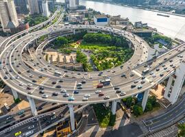 Aerial view of Shanghai highway interchange with heavy car traffic, skyscrapers and bridge infrastructure, the Huangpu River with urban transport