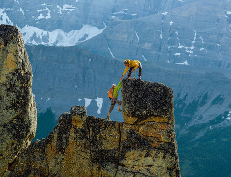 Mountain climber helping another to reach the summit