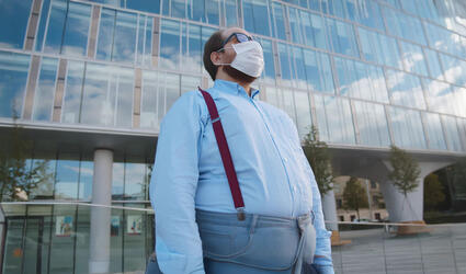 Overweight office employee tired of wearing safety mask outdoors