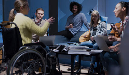 Handicapped young woman with colleagues working in office. 