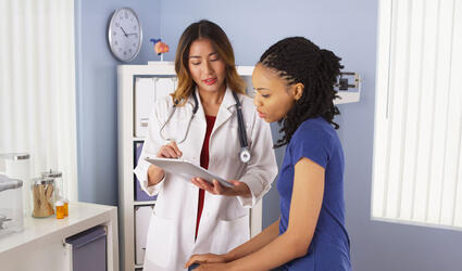 African American patient explaining issues to Asian doctor using tablet