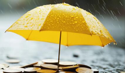 Yellow umbrella covering coins in the rain