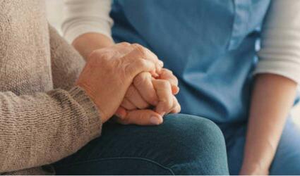 Image of a carer holding an elderly person's hand