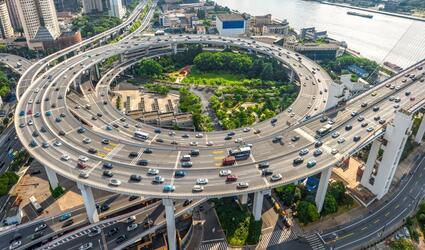 Aerial view of Shanghai highway interchange with heavy car traffic, skyscrapers and bridge infrastructure, the Huangpu River with urban transport